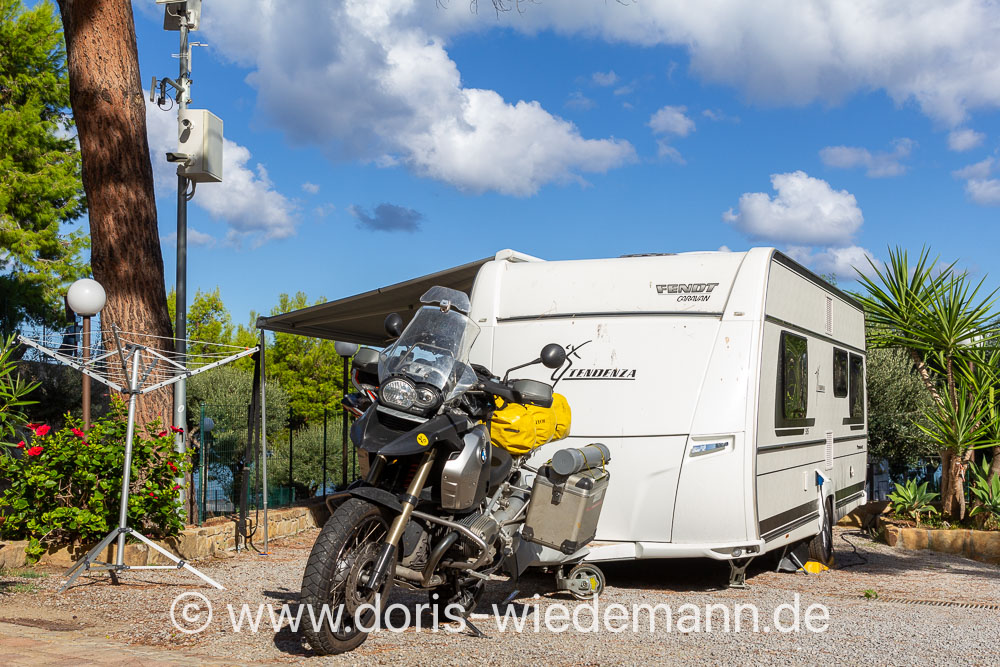 20250929-unbenannt-_MG_6988 Reisemotorrad BMW R1200GS mit Gepäck vor einem Wohnwagen - sieht aus, als würde das Motorrad den Wohnwagen ziehen